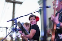 a woman singing and playing guitar in front of a microphone