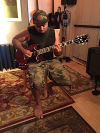 a man in camouflage playing a guitar in a recording studio