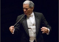 a man in a tuxedo is holding a conductor's baton